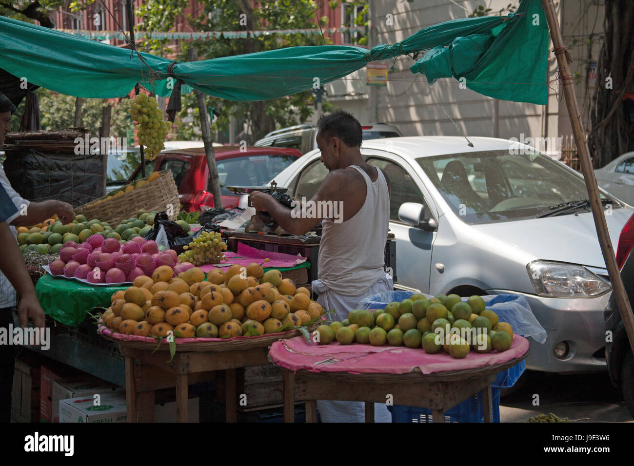 Man buying mangos from a fruit stall in a Kolkata street, Kolkata