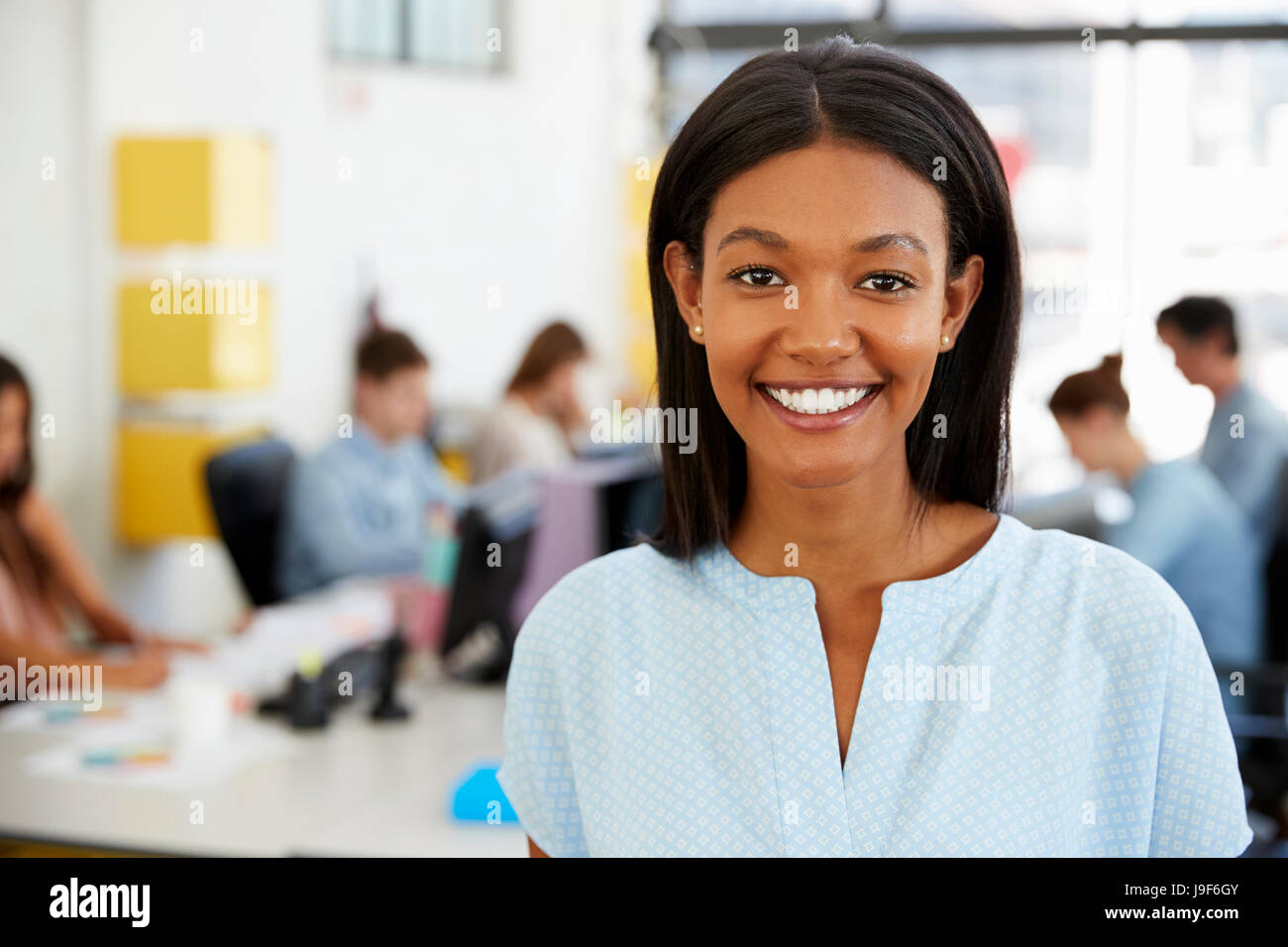 Young black woman smiling to camera in an open plan office Stock Photo ...