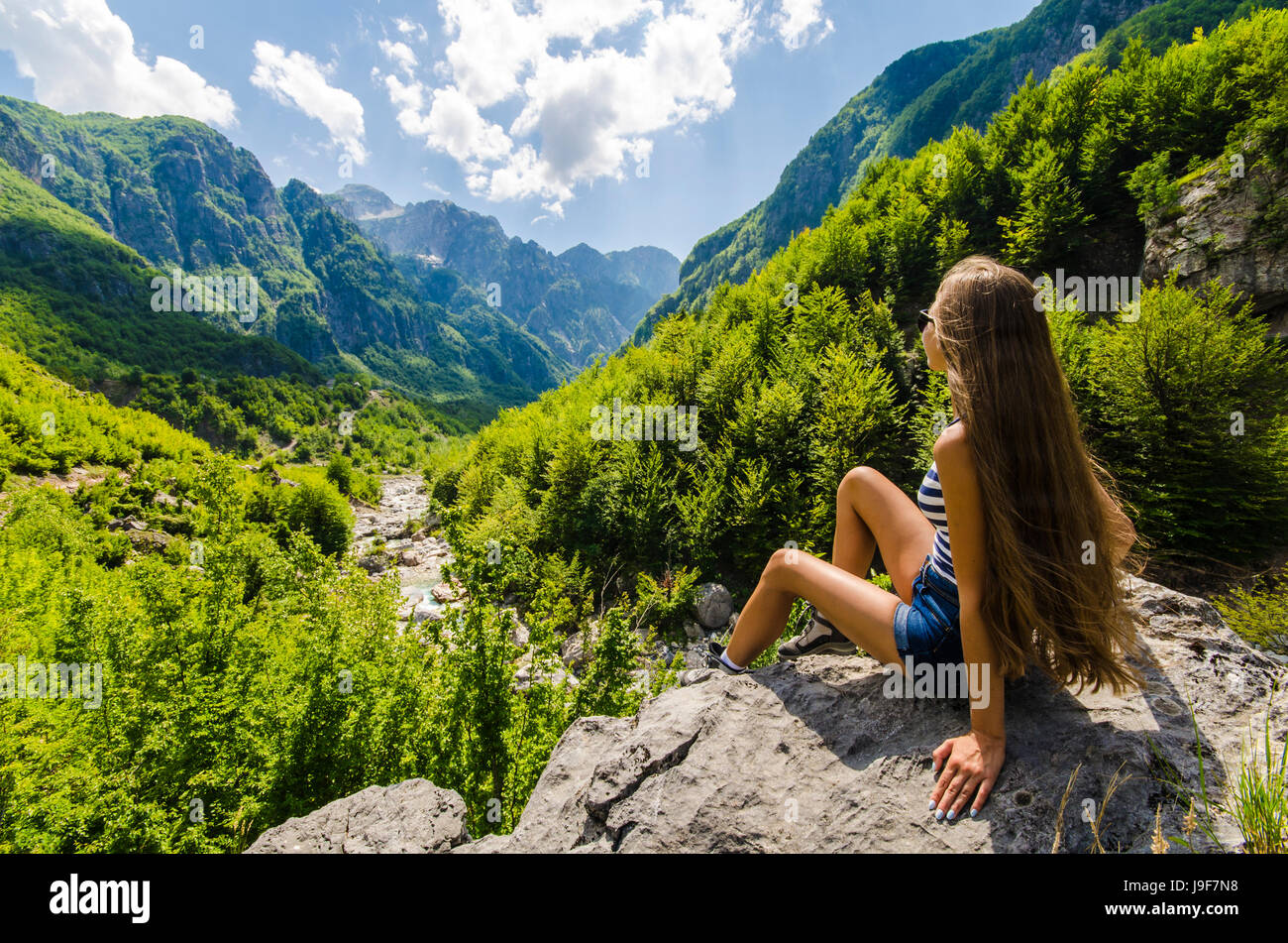Young woman sitting on a rock and looking at beautiful mountains Stock ...