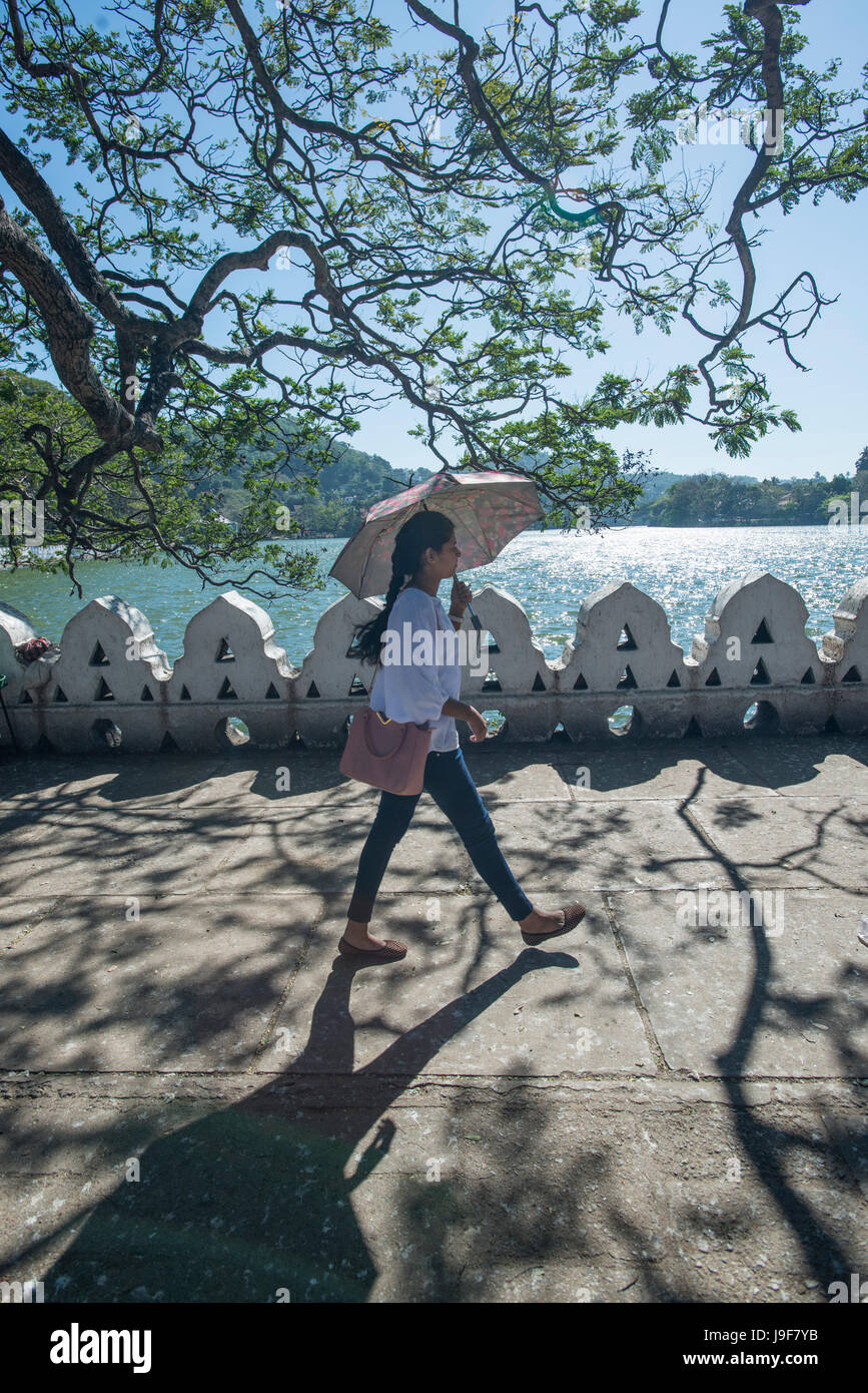 A young woman walks along the promenade next to the lake in Kandy, Sri Lanka Stock Photo
