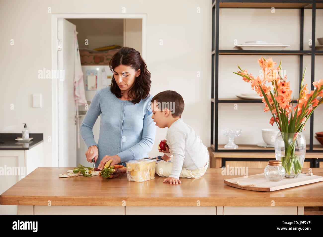 Son Helping Mother To Prepare Food On Kitchen Island Stock Photo
