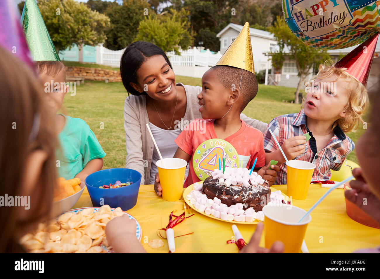 Mother With Children Enjoying Outdoor Birthday Party Together Stock