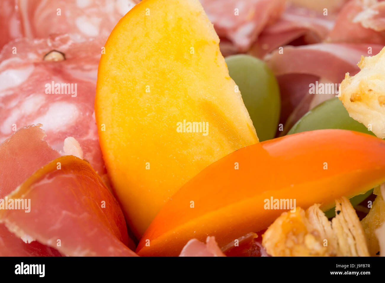 Mixed italian dried meats platter with mango. Macro. Photo can be used as a whole background. Stock Photo