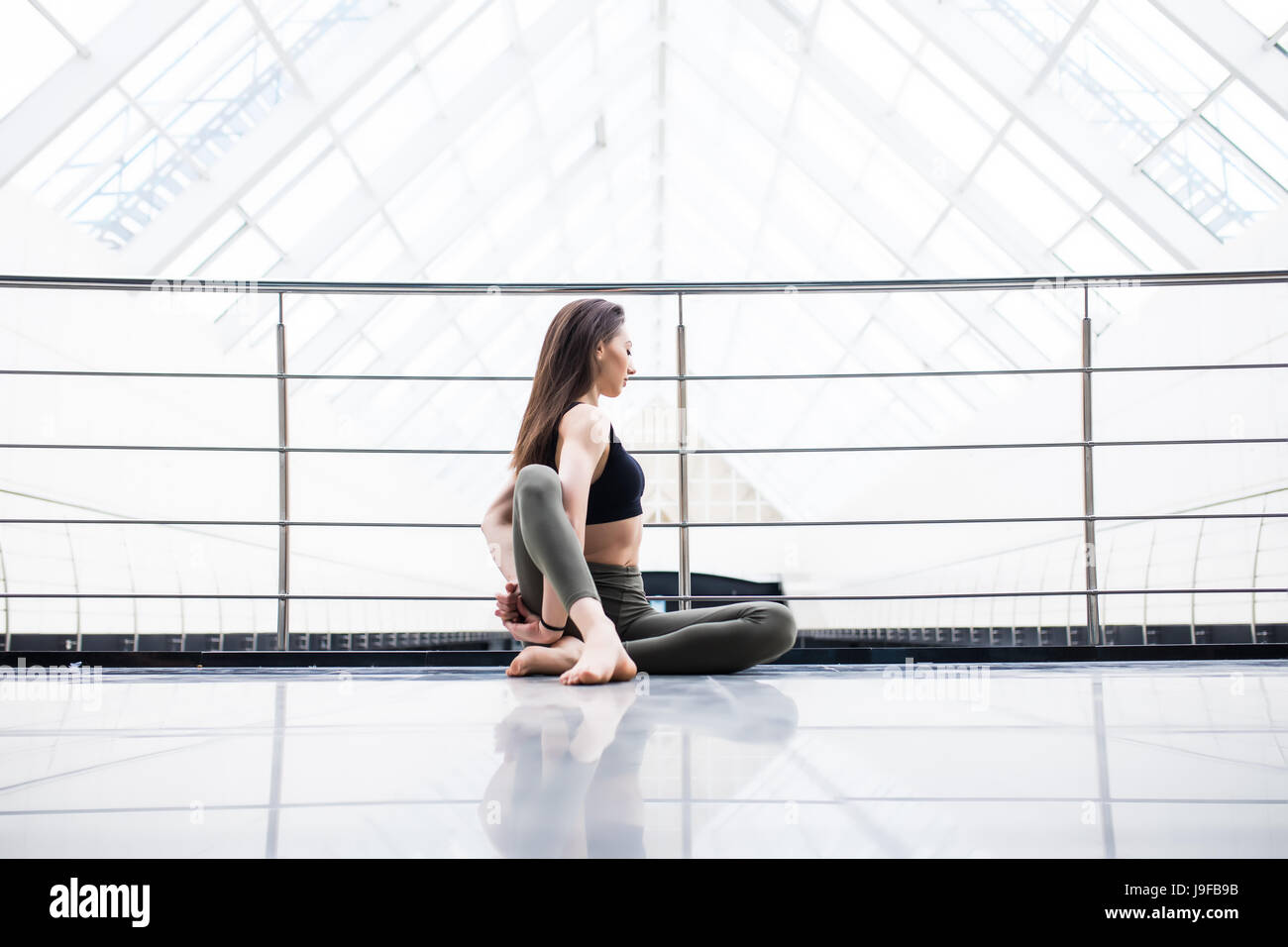 Beautiful yoga woman practice in a big window hall background. Stock Photo