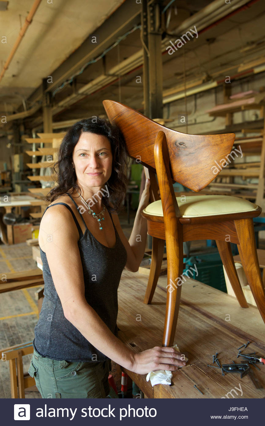 Owner And Designer At A Cabinet Making Shop Poses With A Walnut