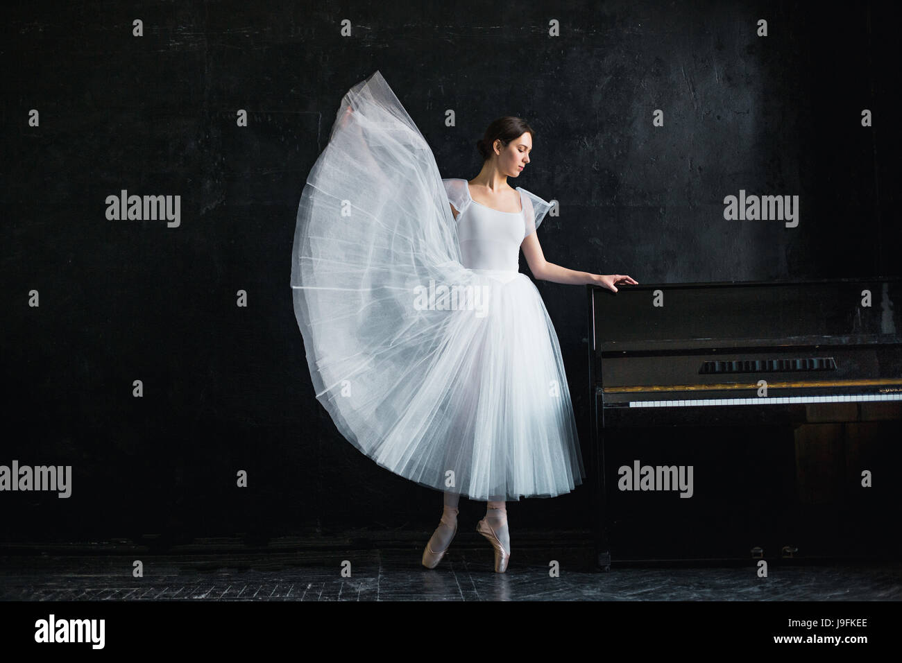 Young and incredibly beautiful ballerina is posing in a black studio Stock Photo