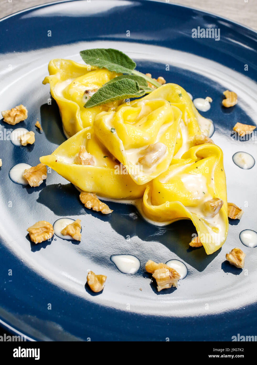 Tortelloni, typical Bologna homemade stuffed pasta, served with nuts, cheese cream and sage Stock Photo