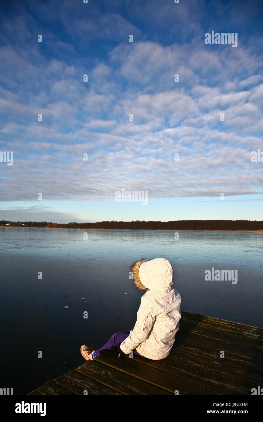 Girl sitting with a view on a beautiful  lake landscape  in scandinavia in denmark Stock Photo
