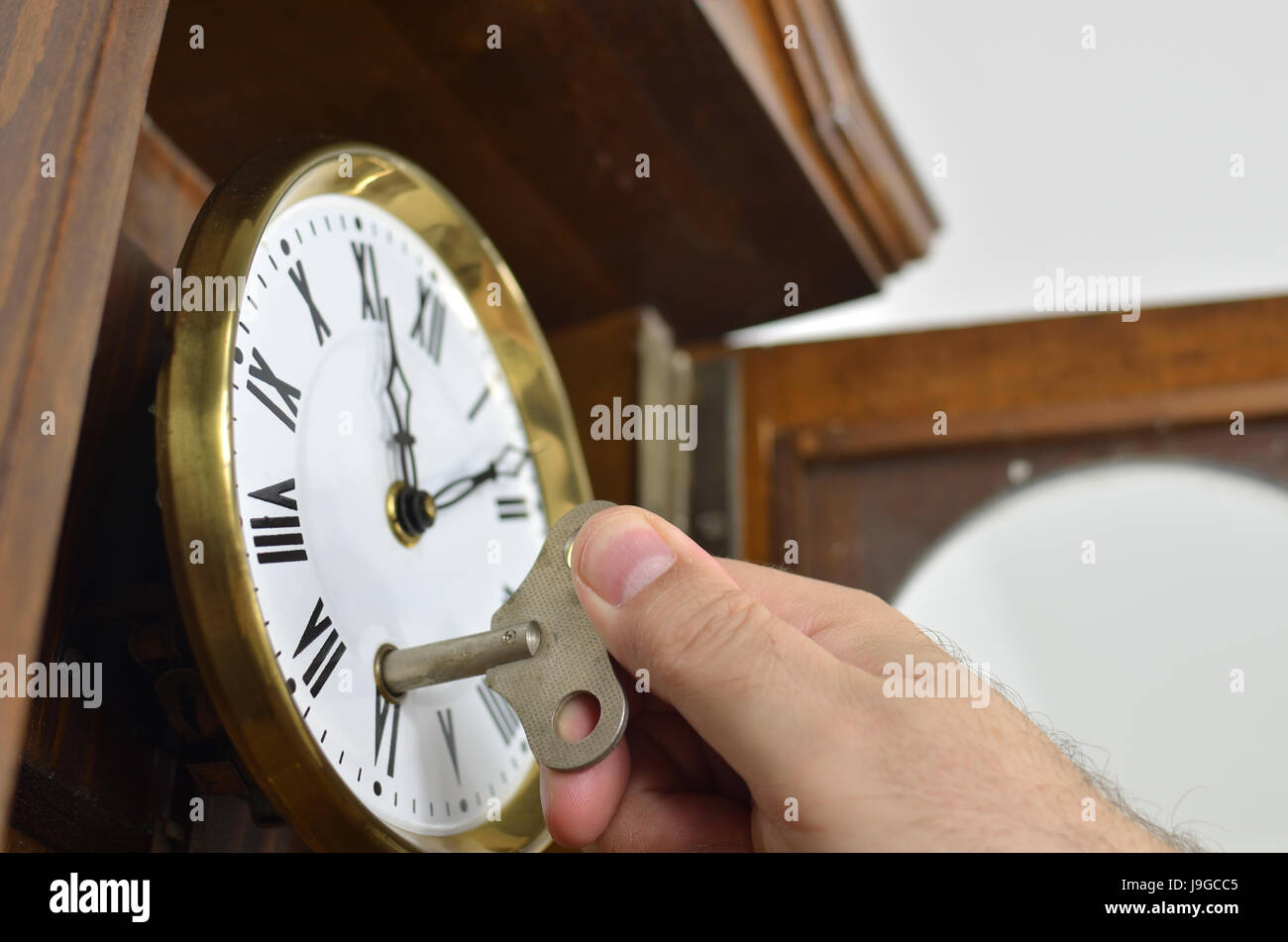 Hand winding a wall clock in retro style with a key Stock Photo Alamy