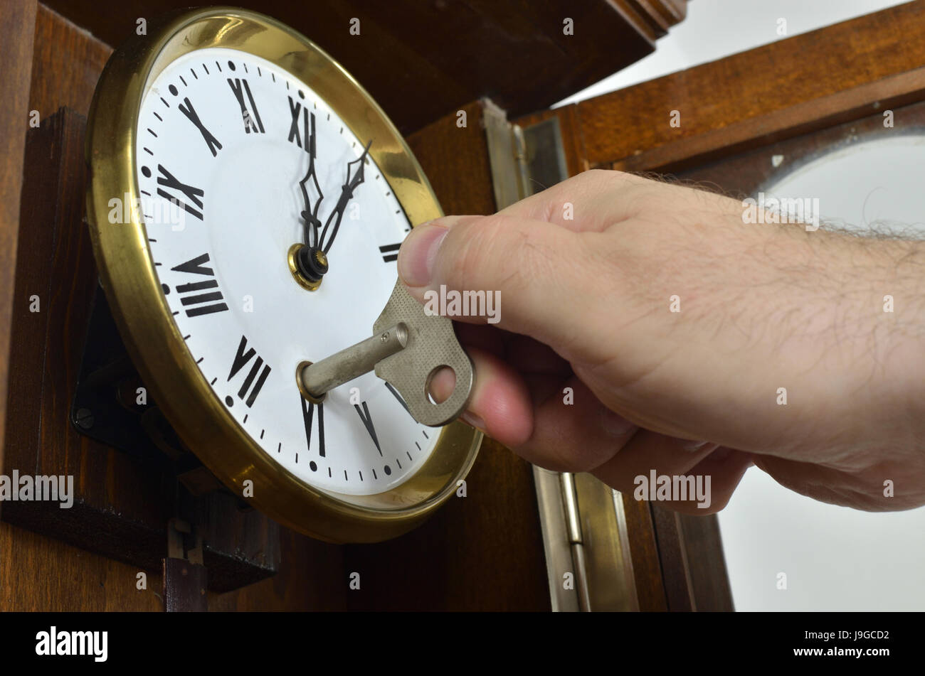 Hand winding a wall clock in vintage style with a key Stock Photo Alamy