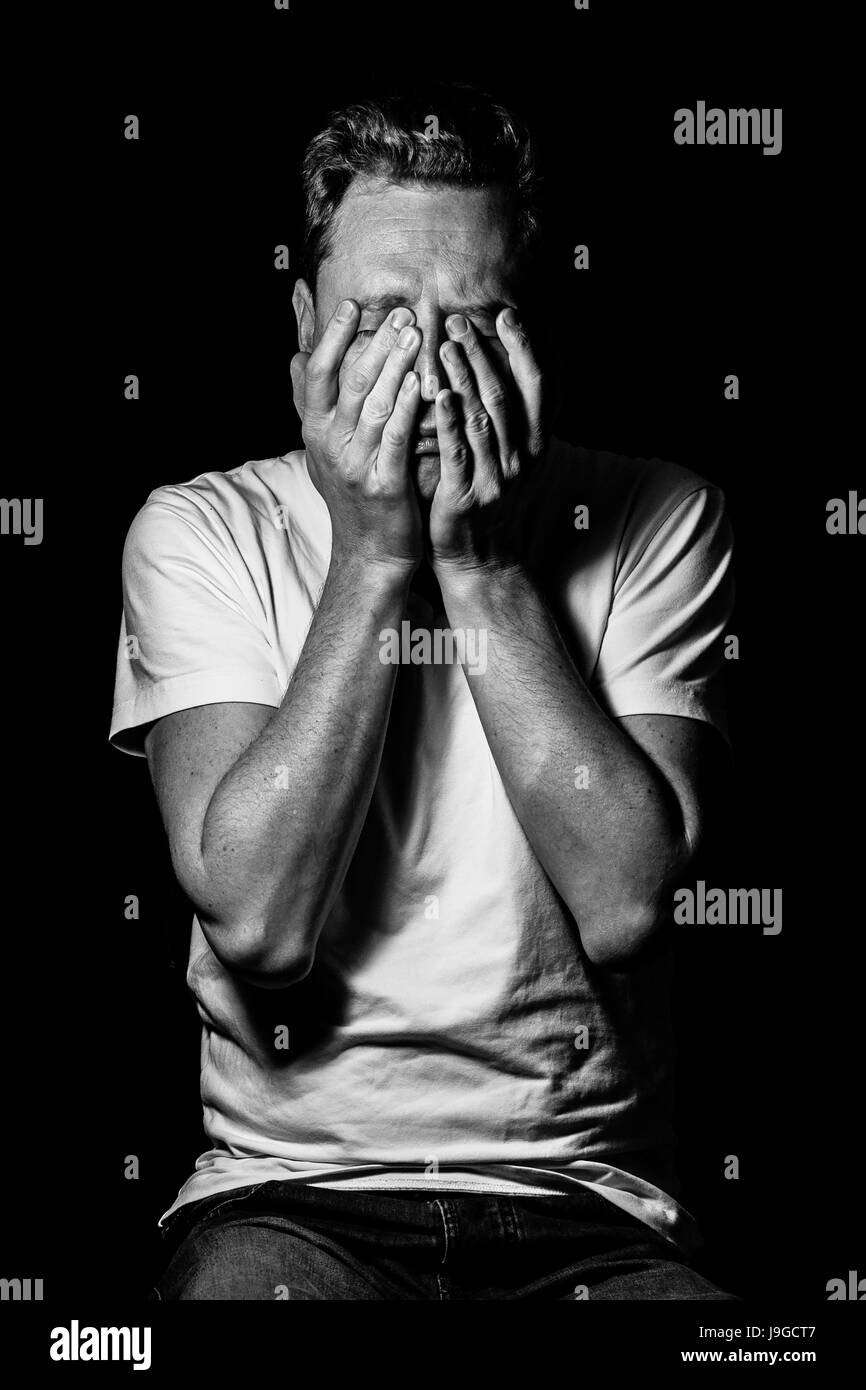 Portrait of a young man hiding his face behind hands, black and white autoportrait of the photographer. Szymon Mucha. Stock Photo