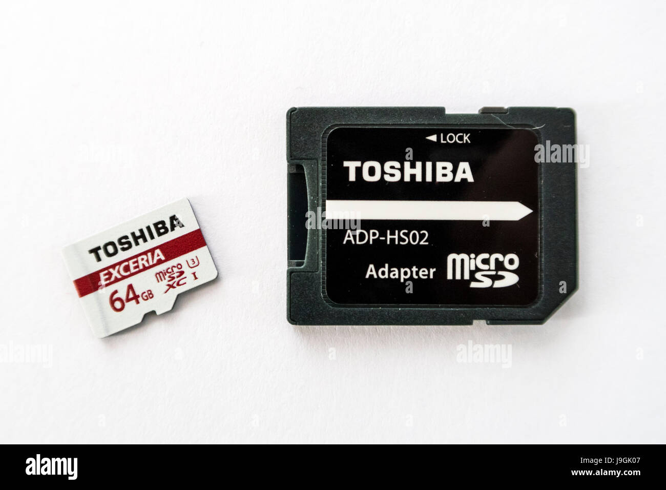 Toshiba Exceria microSD XC memory card with a capacity of 64GB, and a microSD to SD card adapter on white background. Stock Photo