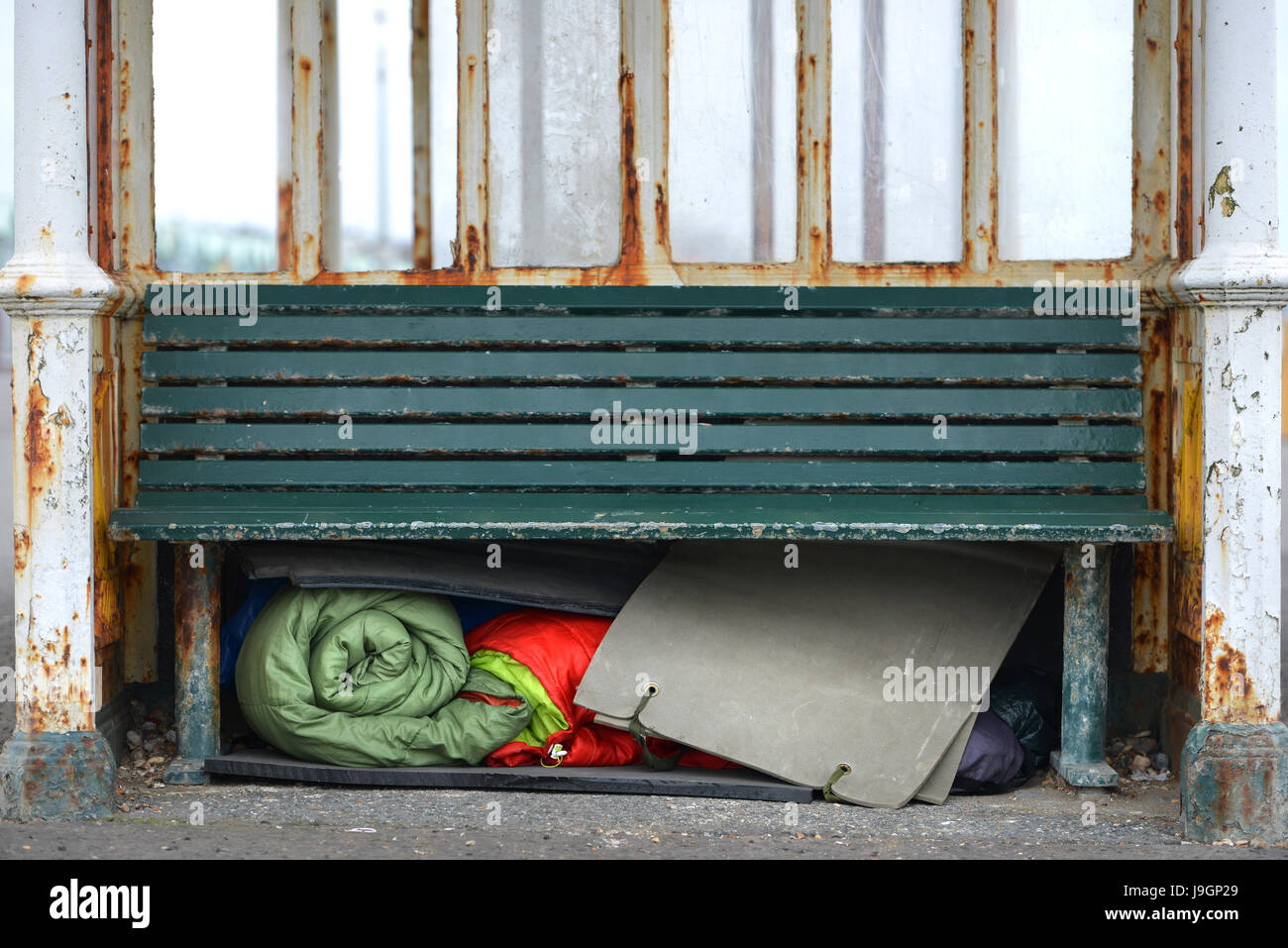 Homelessness. Homeless person's bedding stored under a bench in a bus