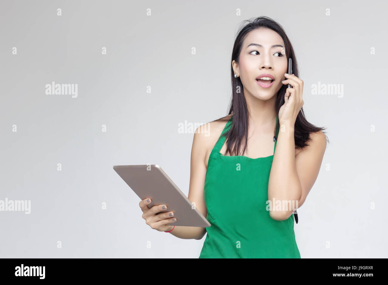 entrepreneur asian lady busy day with mobile and tablet to order sell on gray background Stock Photo