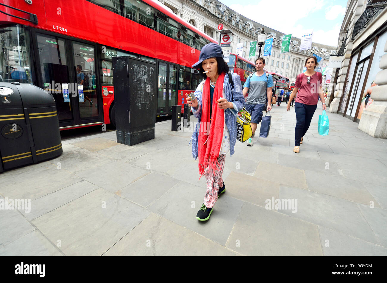 London, England, UK. Colurfully-dressed older woman smoking in Regent Street Stock Photo