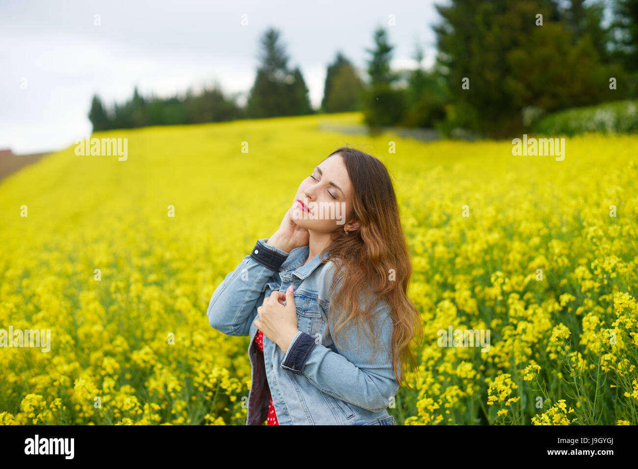 A young caucasian woman in rapeseed field Stock Photo - Alamy
