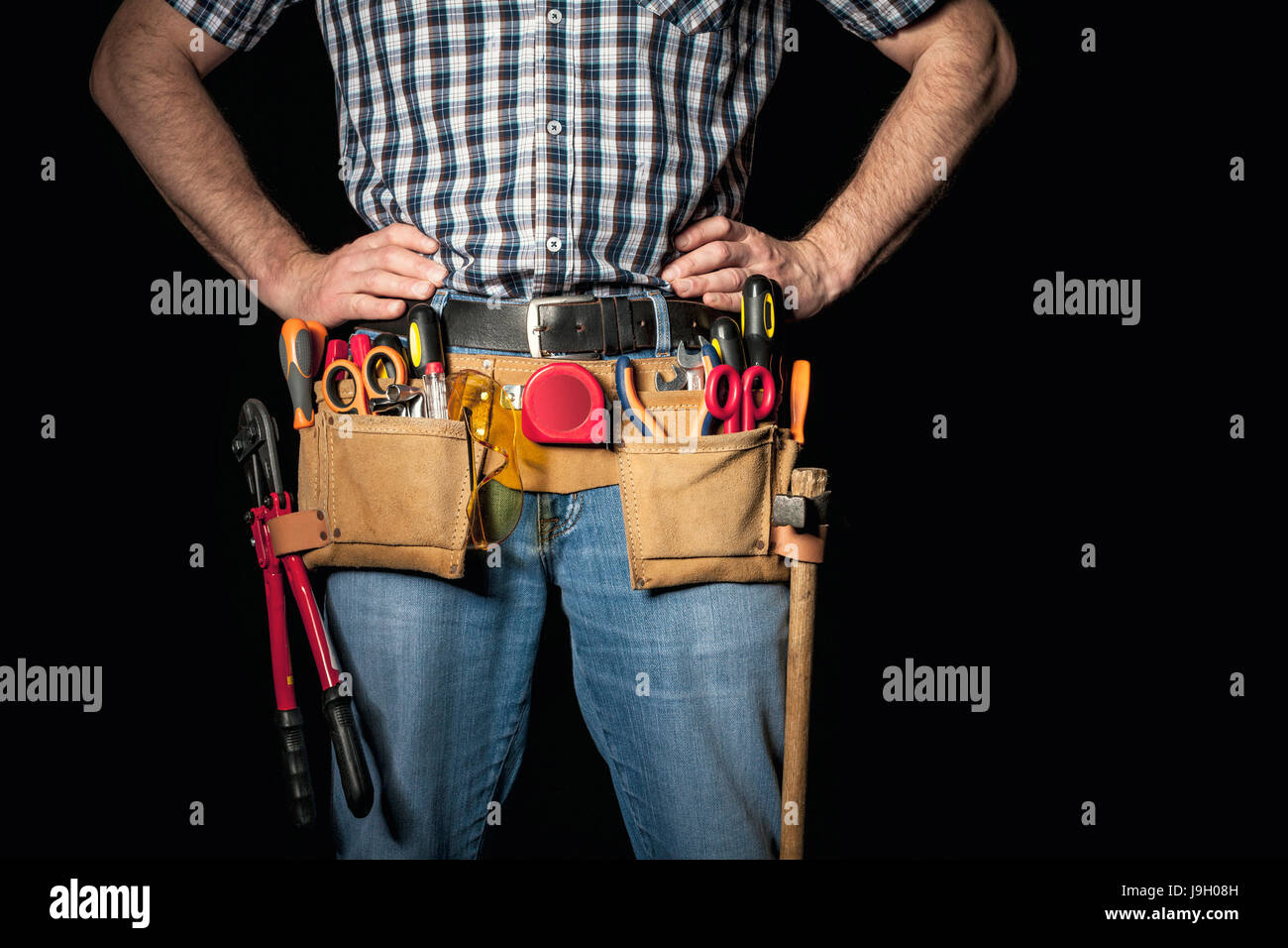 detail of handyman with leather toolsbelt and tools on dark background Stock Photo