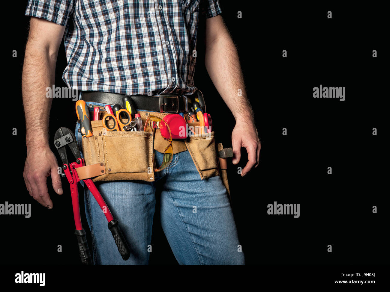 detail of handyman with leather toolsbelt and tools on dark background Stock Photo