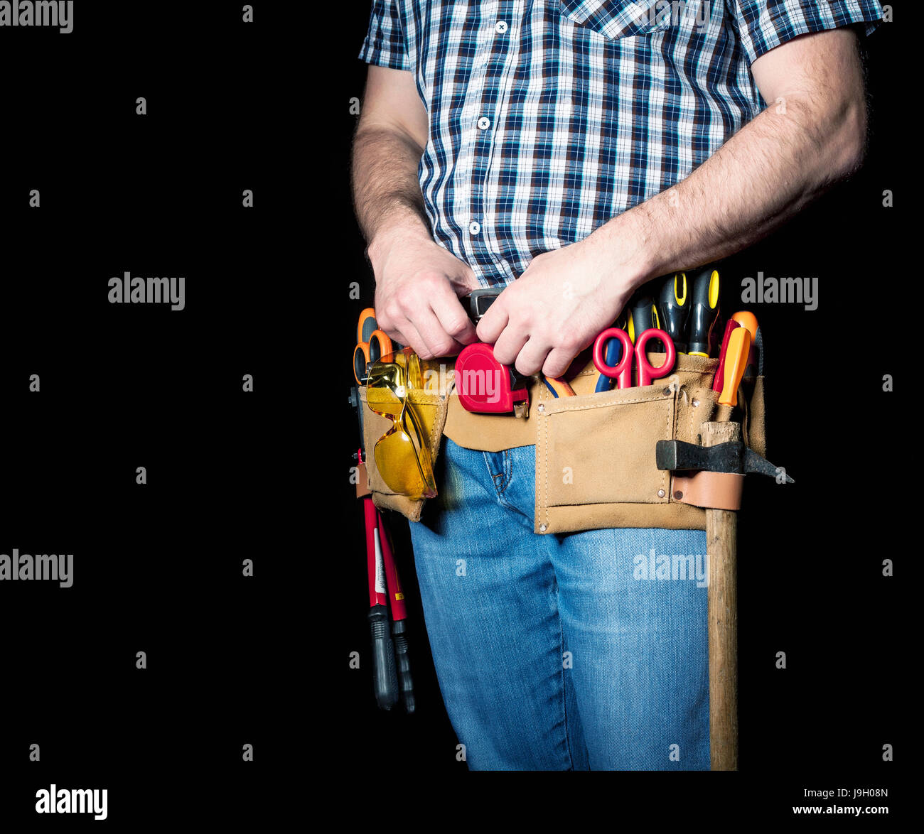 detail of handyman with leather toolsbelt and tools on dark background Stock Photo