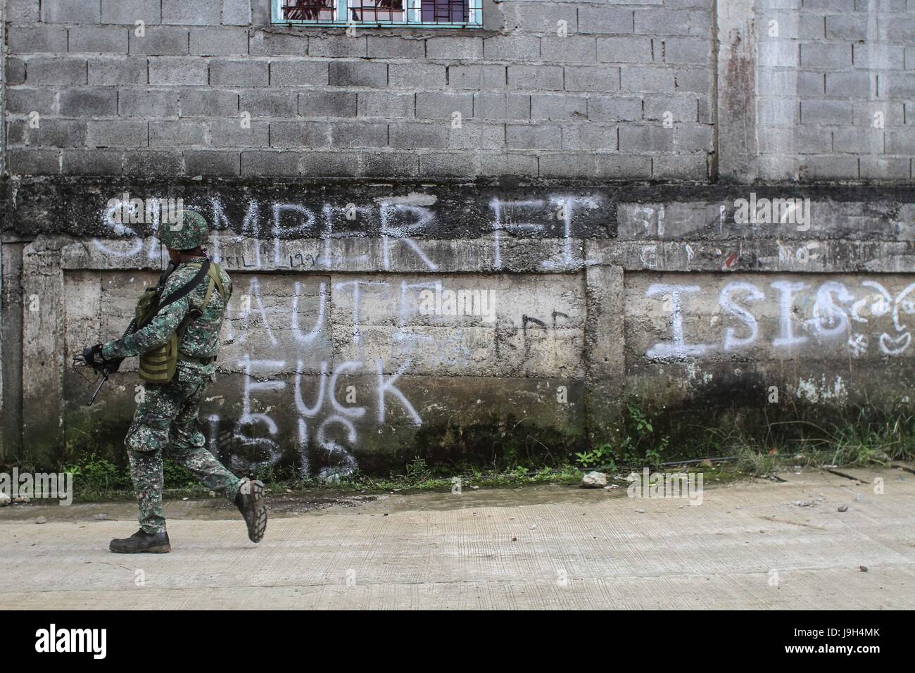 Marawi, Philippines. 2nd June, 2017. A Philipine marine walks past a graffitti in the village of Mapandi, in Marawi City in southern Philippines . June 2, 2017. They advance their positions as they assault the Islamist Militant Maute group. Credit: Linus Guardian Escandor Ii/ZUMA Wire/Alamy Live News Stock Photo