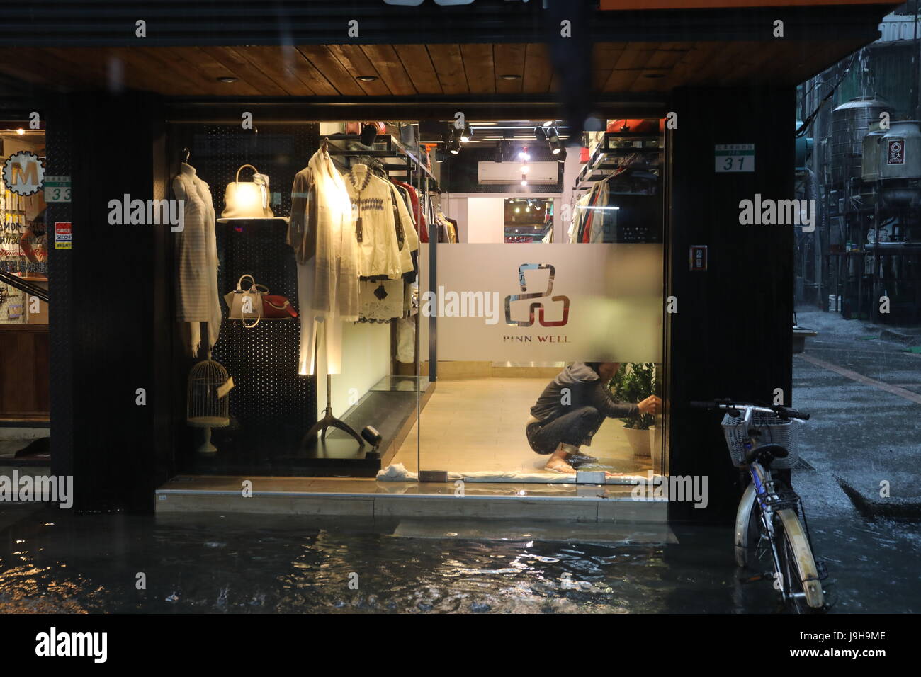 Taipei, Taiwan. 2nd June, 2017. A shop owner seals the door to her shop in central Taipei to keep the water out as the monsoon rain, also called the plum rain, begins on June 2, flooding large areas of northern Taiwan. Credit: Perry Svensson/Alamy Live Credit: Perry Svensson/Alamy Live News Stock Photo