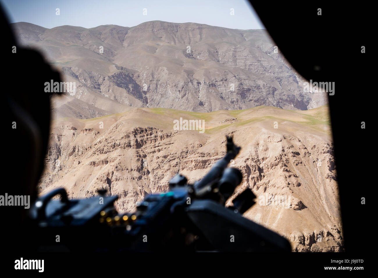 A U.S. Army door gunner watches the hills during a flight in a UH-60 Black Hawk helicopter assigned to Task Force Griffin, 16th Combat Aviation Brigade, reloads weapons and fuel before departing on a mission in support of Operation Resolute Support May 1, 2017 in Kunduz, Afghanistan. Kunduz has seen increased Taliban activity as more than 8,000 American troops and 6,000 from NATO and allied countries continue to assist the government. Stock Photo