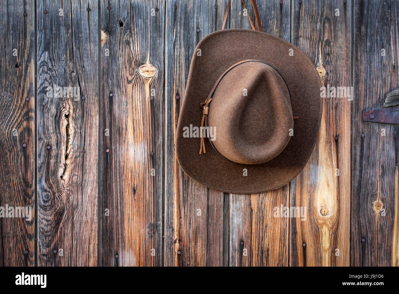 brown wool felt cowboy hat with leather headband hanging on weathered