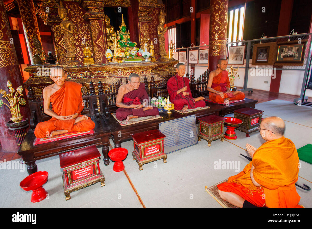 Thailand, Chiang Mai, Wat Phra Sing, Monk Praying to Lifesized Fibreglass Models of Deceased Temple Abbots Stock Photo