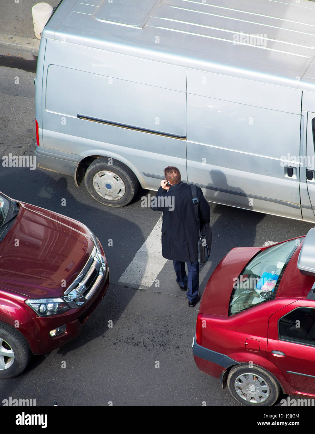 Businessman crossing the road in traffic jam. Aerial view Stock Photo