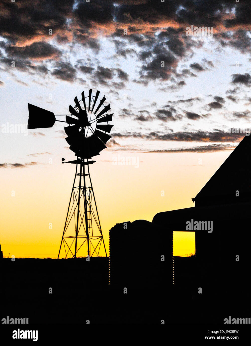 An Australian farm house with windmill in silhouette against a flecked