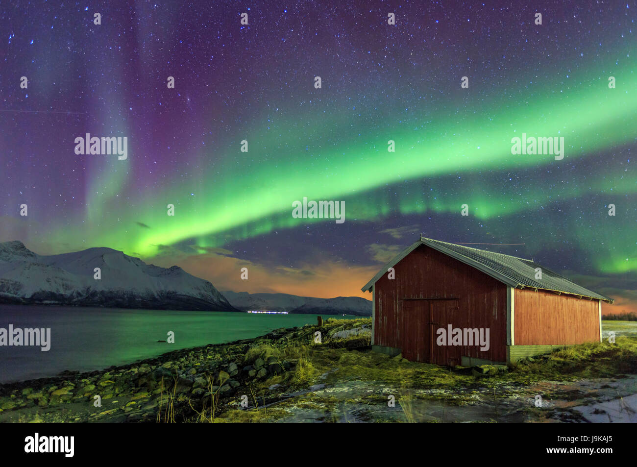 Northern Lights Illuminates The Wooden Cabin At Svensby Lyngen
