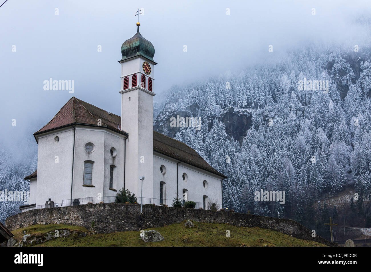 Clouds and mist on the alpine church of Wassen surrounded by snowy woods Canton of Uri Switzerland Europe Stock Photo