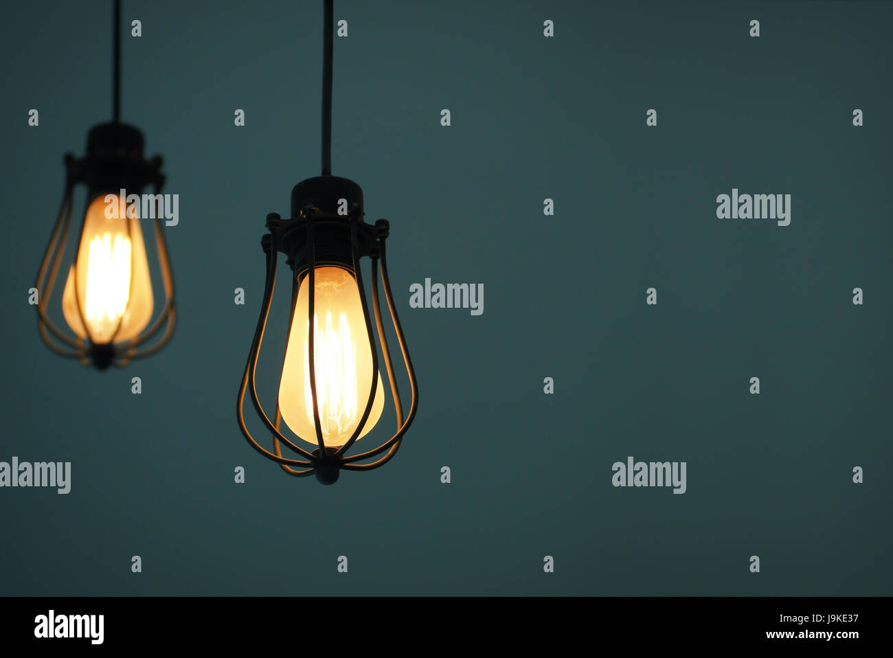Yellow illuminated hanging light bulbs on navy plain background with ...