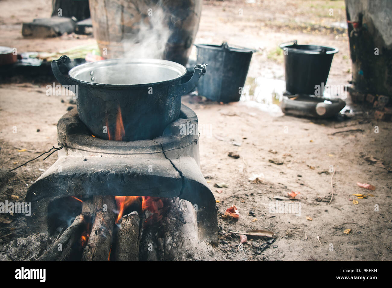 old aluminium pot on stove. water is boiling for cook in hut at the