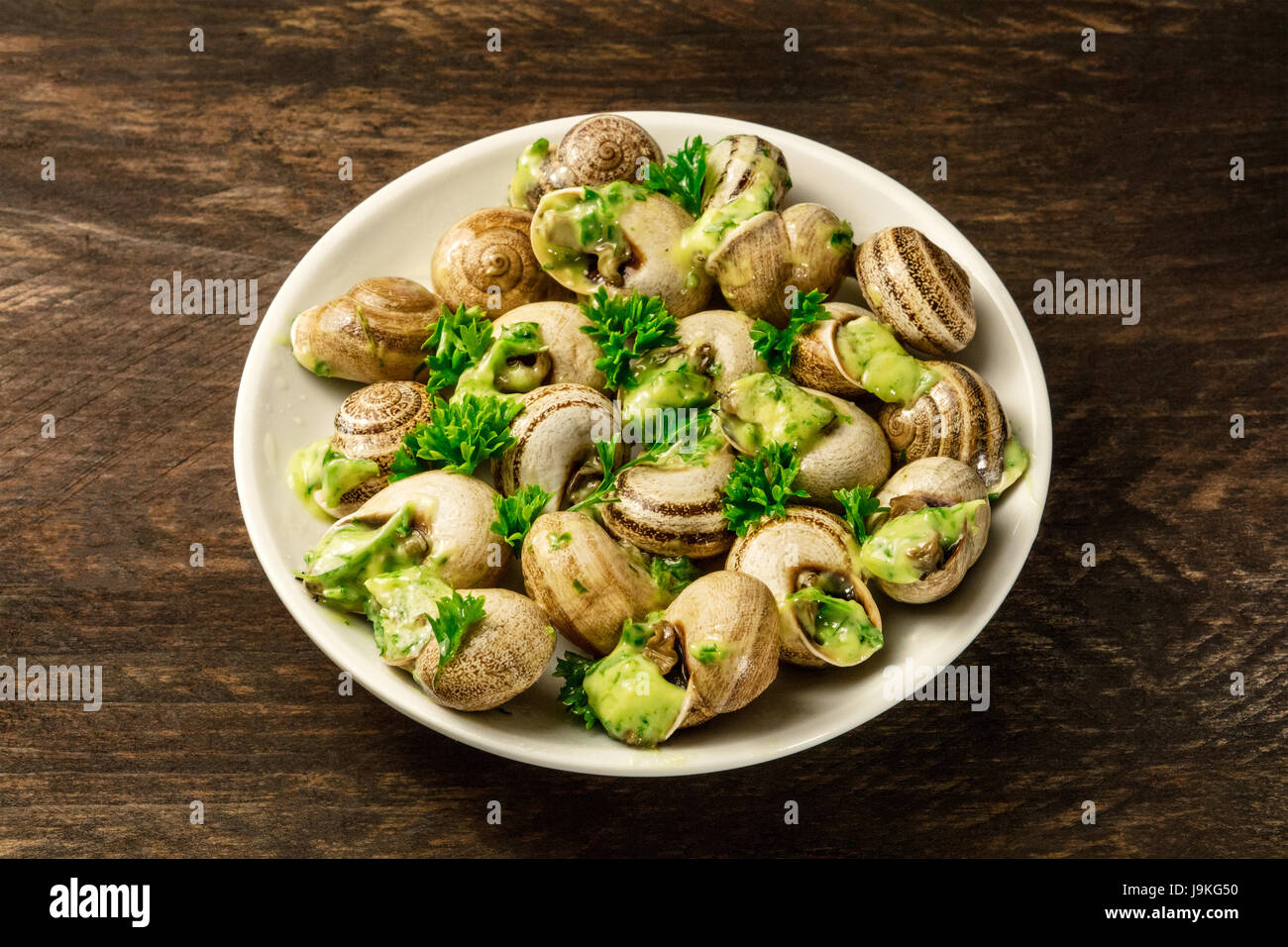 A photo of escargots a la bourguignonne, a plate of snails with the typical French green sauce
