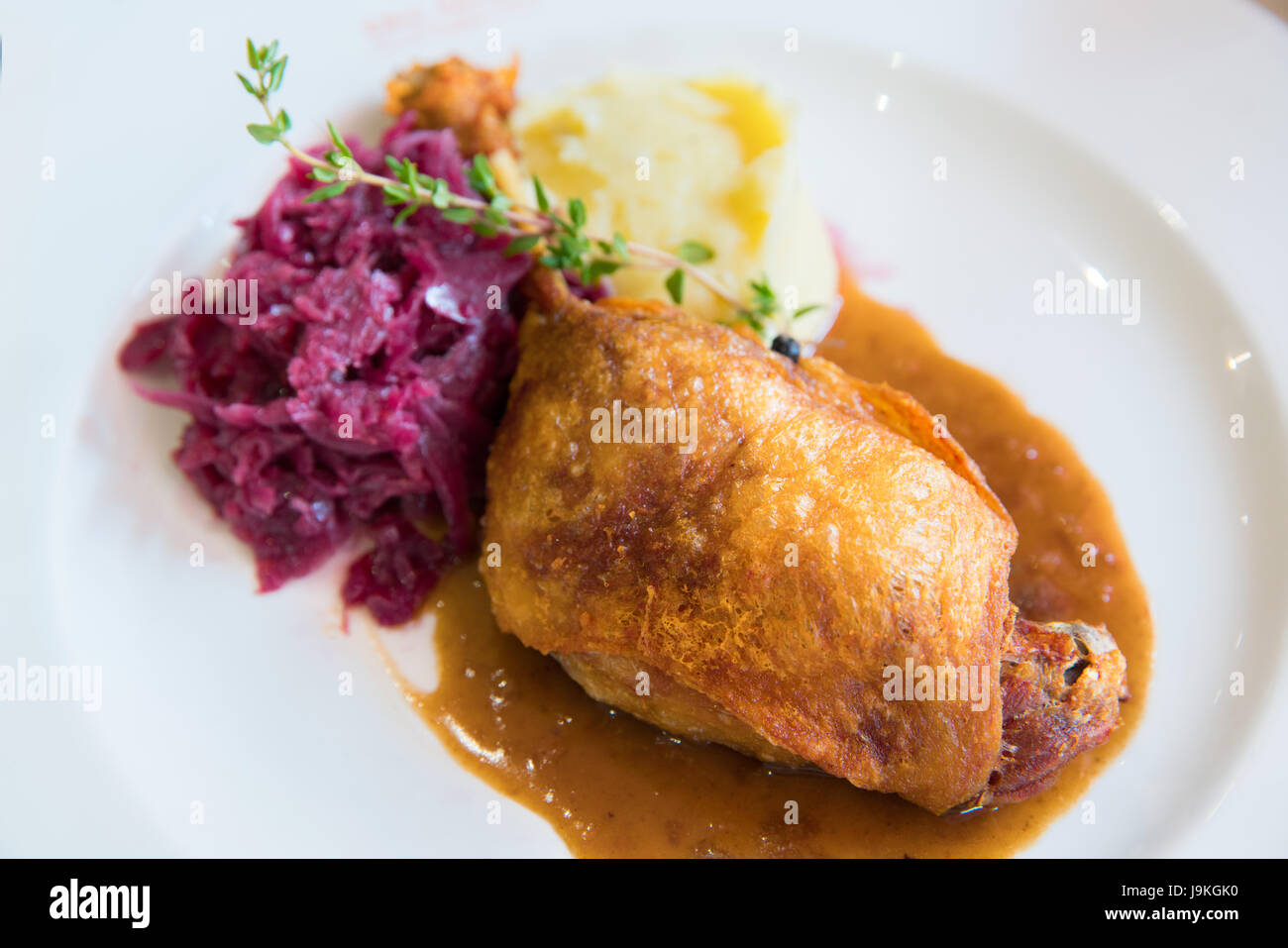 Duck confit with purple cabbage and mashed potato on white plate Stock Photo