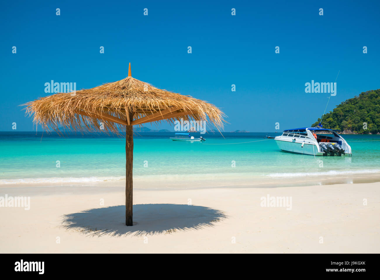 Beach Umbrella made of leafs on white beach in front of Sea day time blue sky wide shot background, Nyaung Oo Phee, Myanmar Stock Photo