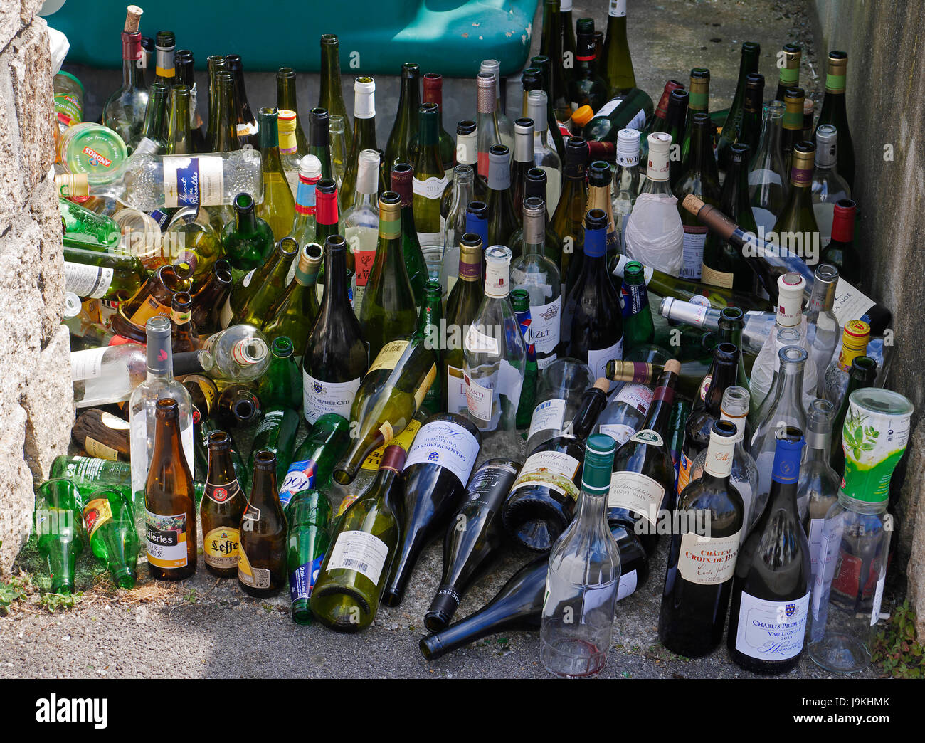 Deposit of empty bottles near a waste container on a street in summer