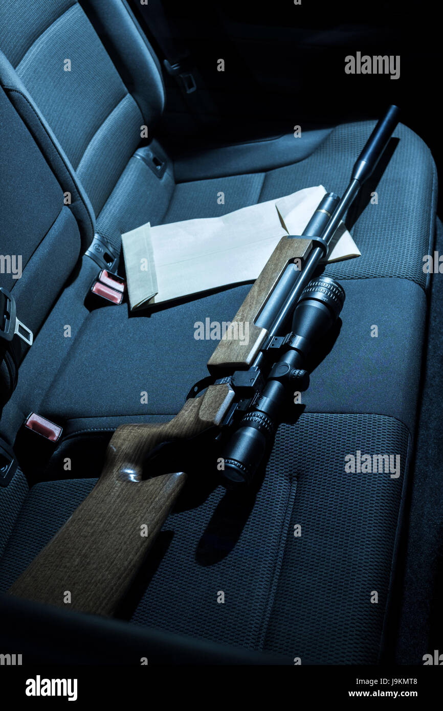 A gun and envelope on the back seat of a car. Stock Photo
