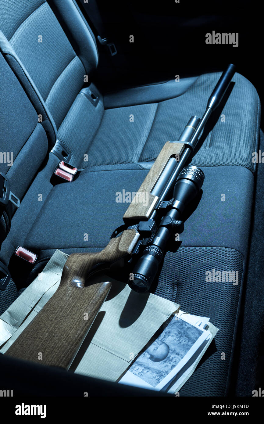 A gun and photographs on the back seat of a car. Stock Photo