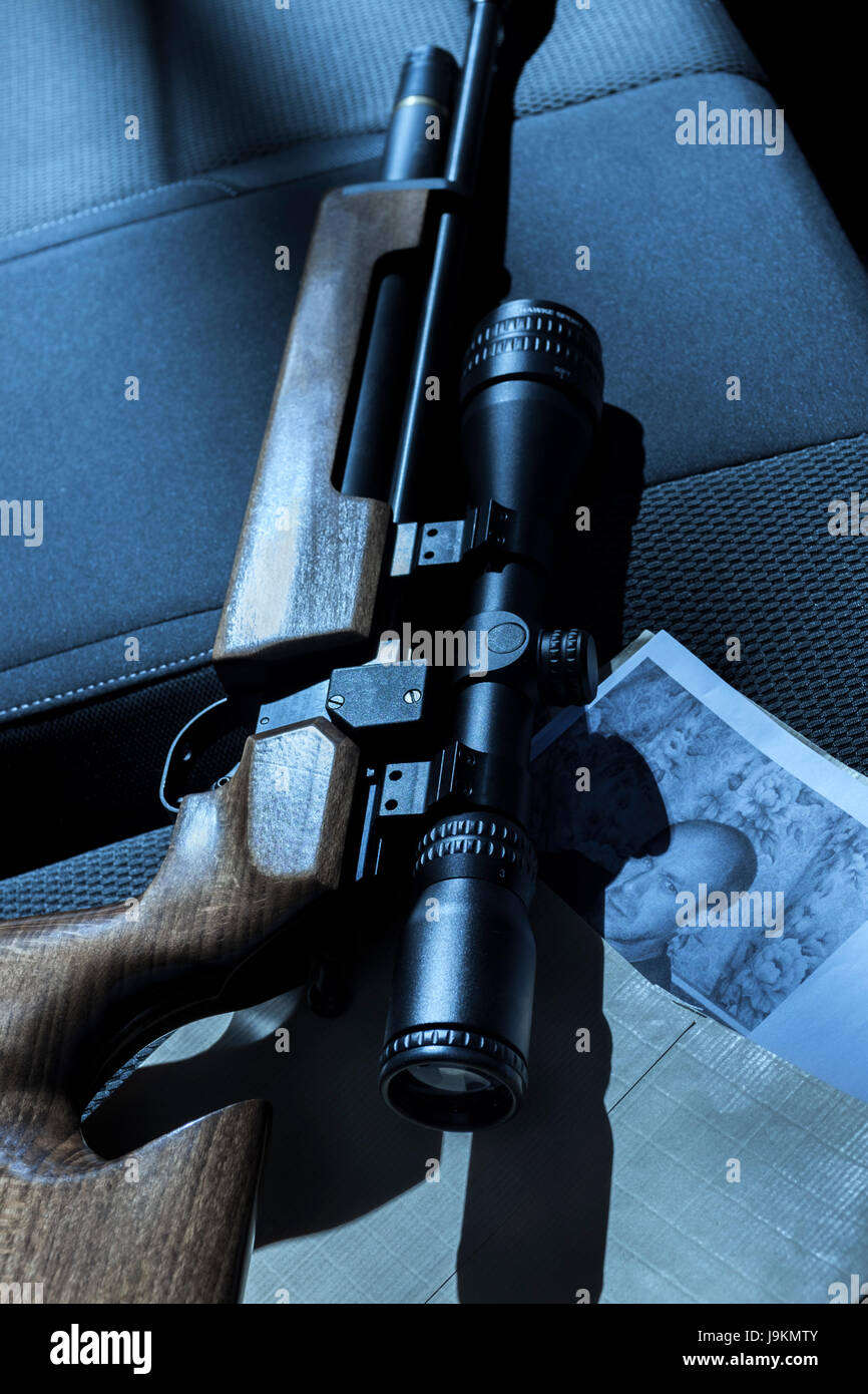 A gun and photographs on the back seat of a car. Stock Photo