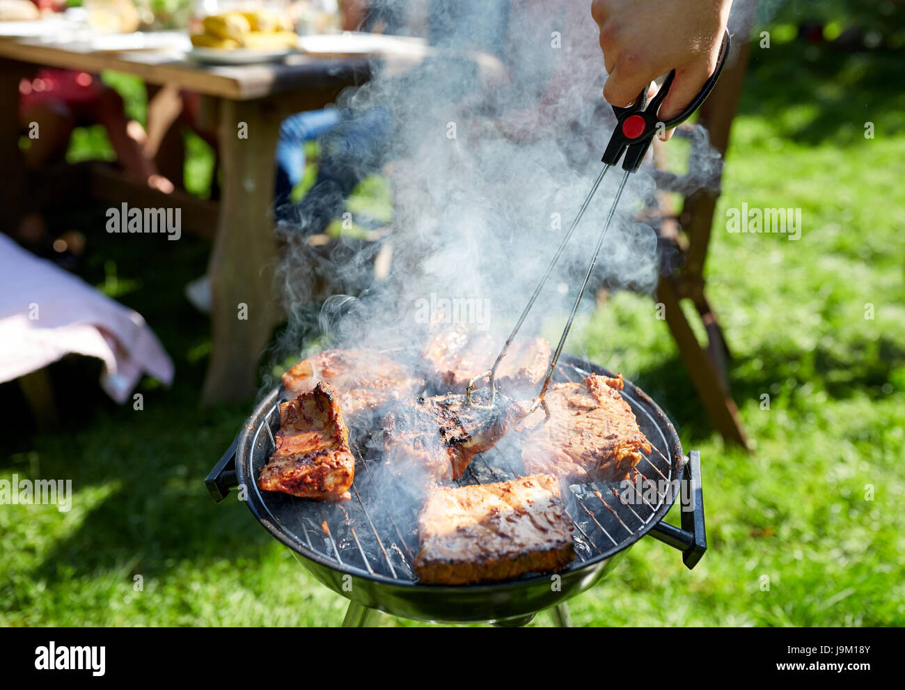 man cooking meat on barbecue grill at summer party Stock Photo Alamy