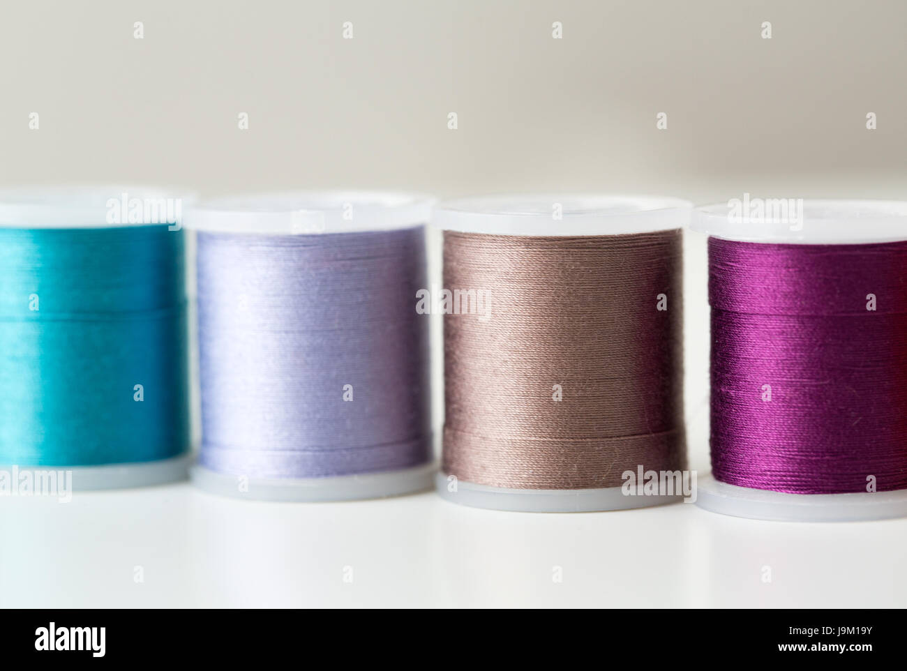 row of colorful thread spools on table Stock Photo - Alamy