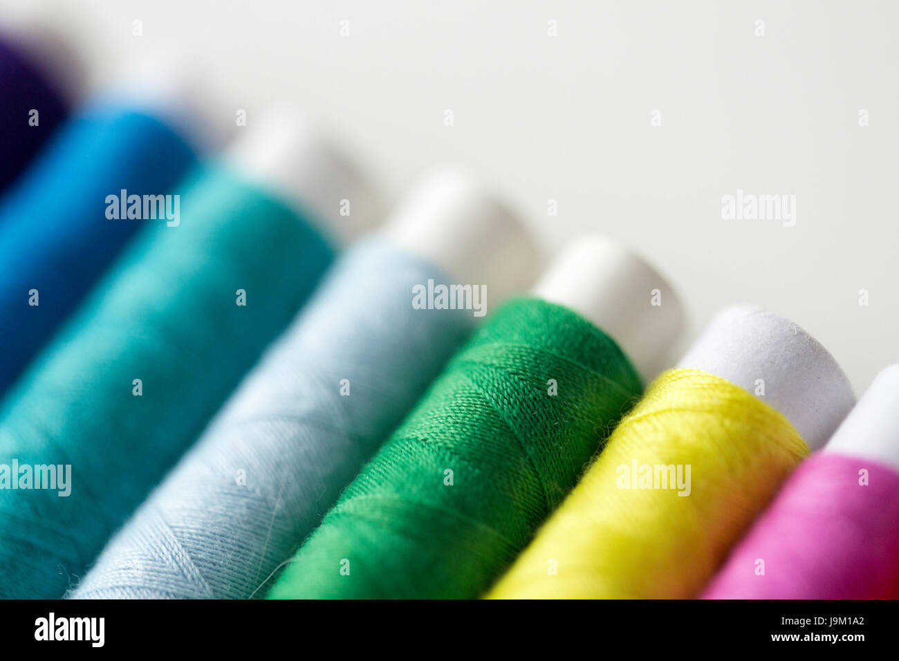 row of colorful thread spools on table Stock Photo - Alamy