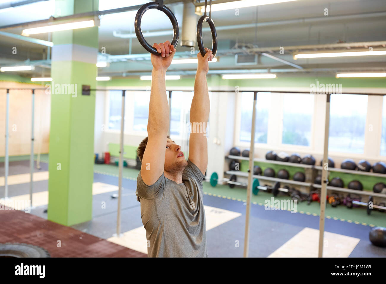 man exercising and doing ring pull-ups in gym Stock Photo