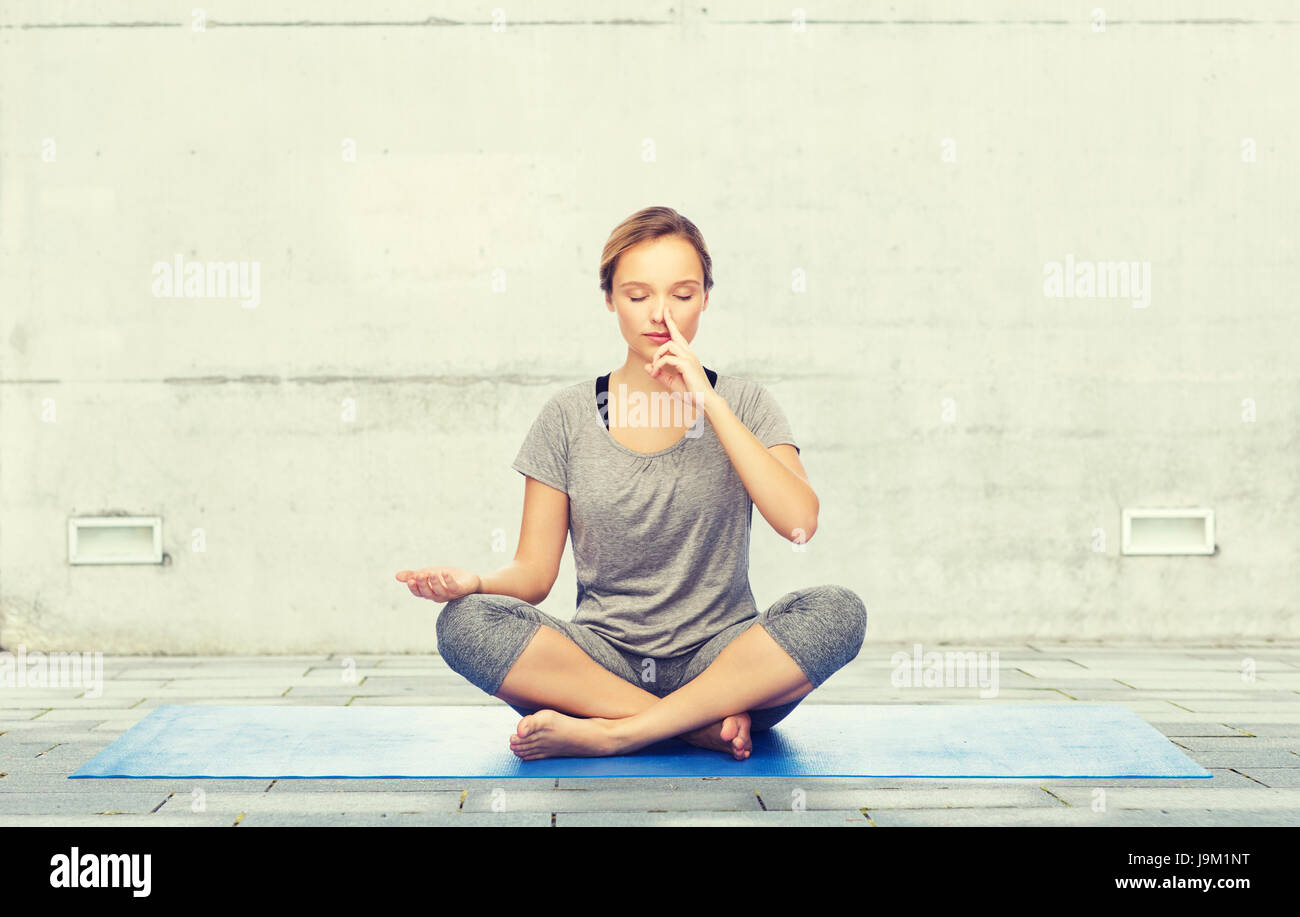 woman making yoga meditation in lotus pose on mat Stock Photo - Alamy