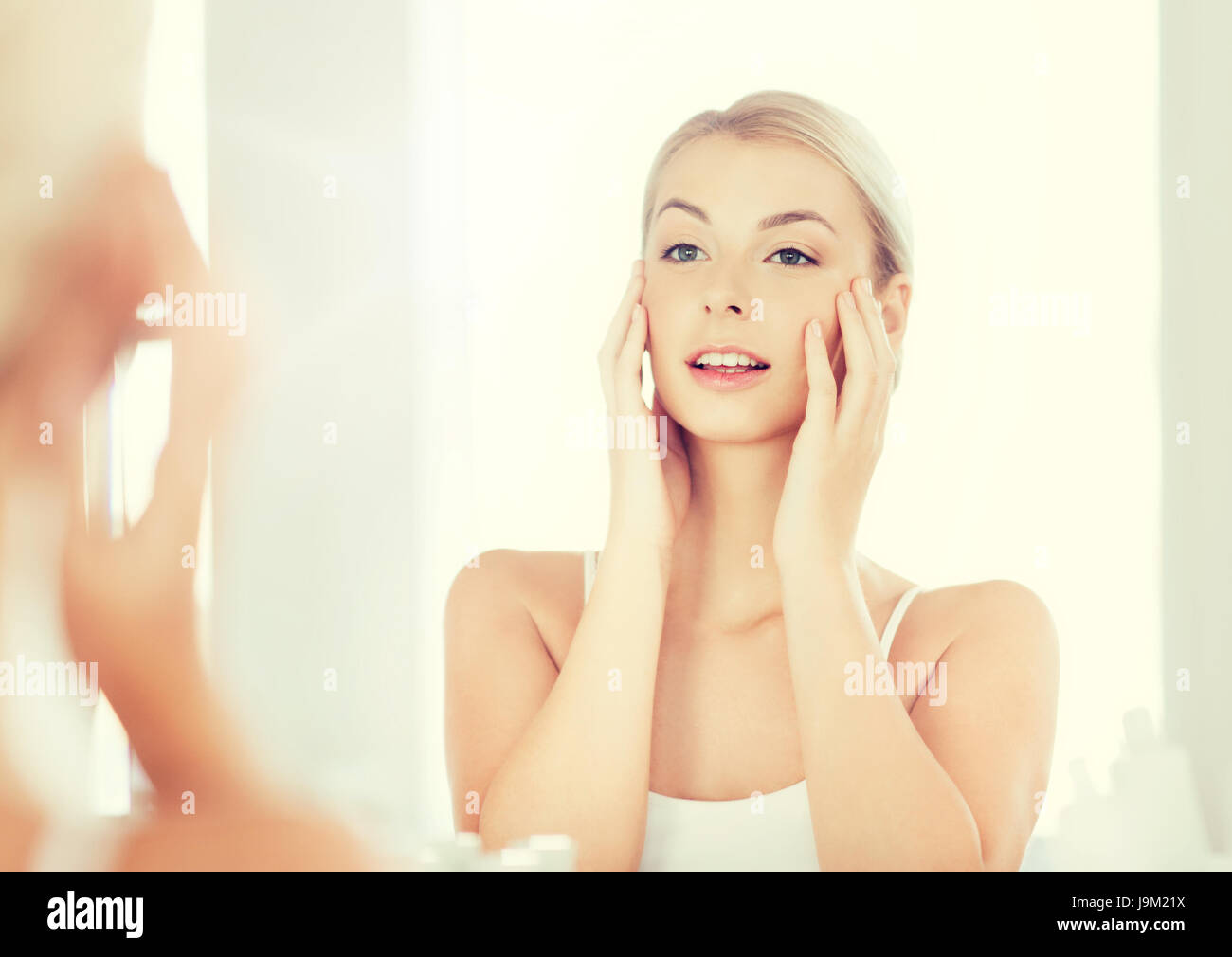 happy young woman looking to mirror at bathroom Stock Photo - Alamy