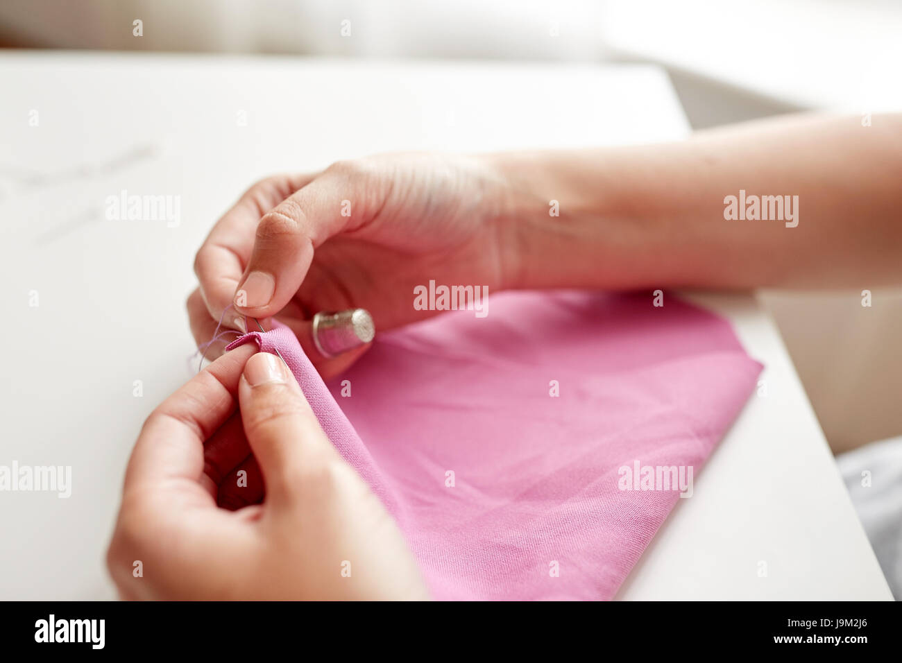 woman with needle stitching fabric pieces Stock Photo