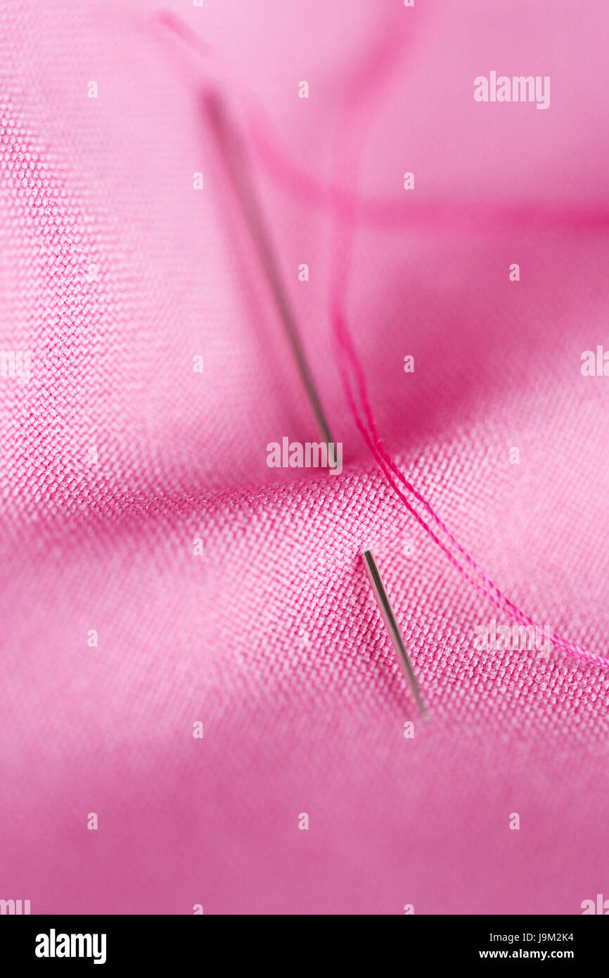 sewing needle with thread stuck into pink fabric Stock Photo Alamy