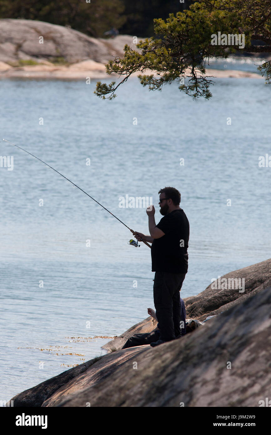 STENDÖRREN Naturereserve a man fishing from the cliffs outside Nyköping Södermanland 2017 Stock Photo